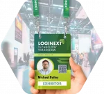 A hand holds an oversized event credential on a branded lanyard